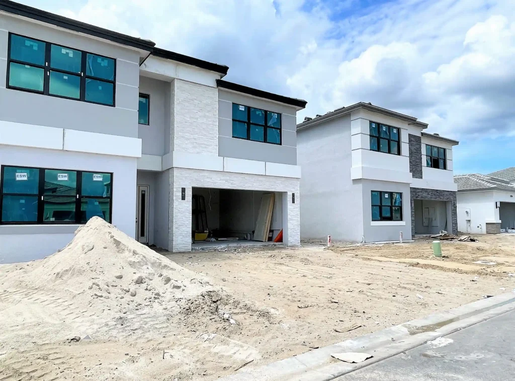 Modern row of townhouses under construction with large blue-tinted windows and light gray/white facades